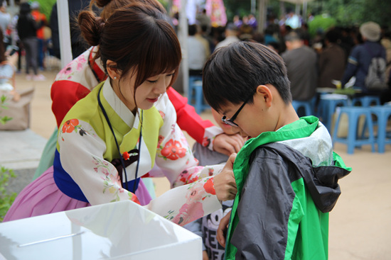 한복소녀단들이 행사에 참여한 사람들에게 개천절 기념 뱃지를 달아주고 있다.