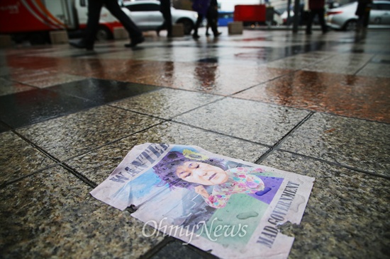 팝아트 작가 이하씨가 지난 2014년 10월 20일 오전 서울 종로구 동화면세점 옥상에 살포한 박근혜 대통령 풍자 '삐라'가 비에 젖은 채 바닥에 떨어져 있다.