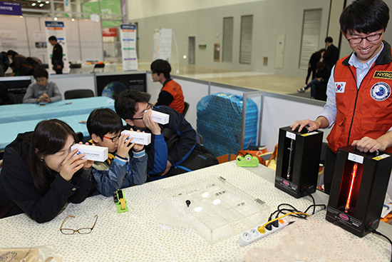 대한민국과학창의축전에 참가한 한 가족이 분광경을 이용해 분광기에서 나오는 수소원소의 성분을 확인하고 있다.
