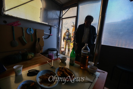 9일 오후 서울 강남구 구룡마을 7-B지역에서 화재가 발생해 한 주민이 차려진 술상을 두고 대피했다.