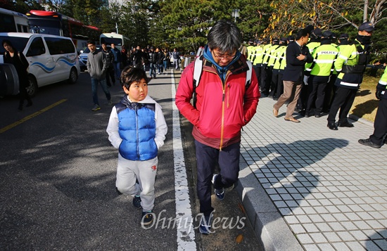  이창근씨가 고개를 숙인 채 아들과 나란히 걷고 있다. 