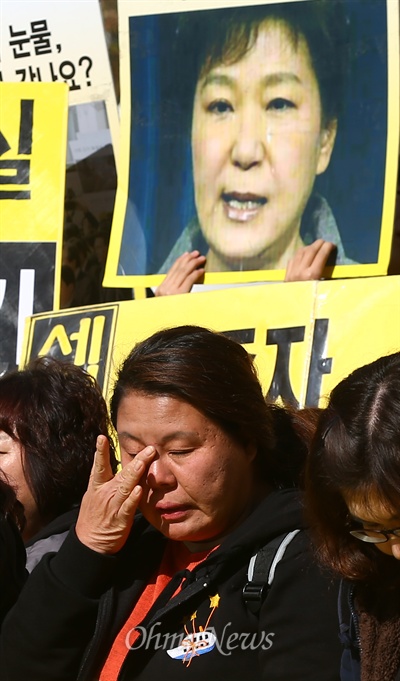 14일 오전 서울 광화문 세월호희생자 농성장 앞에서 열린 세월호참사진상규명을위한 범국민서명호소 기자회견에서 한 유가족이 눈물을 흘리는 모습 뒤로 박근혜 대통령의 눈물 사진이 보이고 있다.  
