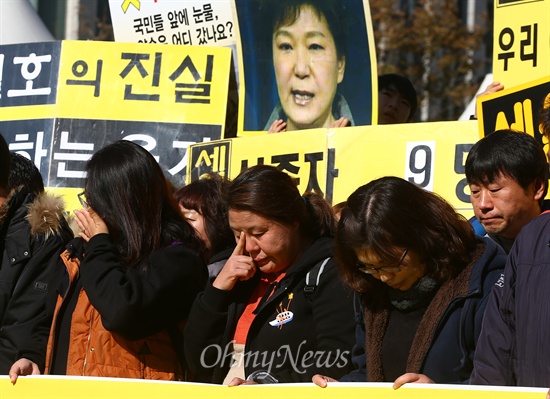 지난 14일 오전 서울 광화문 세월호희생자 농성장 앞에서 열린 세월호참사진상규명을위한 범국민서명호소 기자회견에서 눈물 흘리는 유가족들 뒤로 박근혜 대통령의 눈물 사진이 보이고 있다.