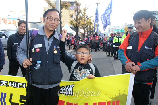 올해 7살인 안병석군이 아버지와 함께 지난 23일 오후 진주에서 열린 "삼성전자서비스 진주센터 폐업철회 결의대회"에 참석해 거리행진하며 구호를 외치고 있다.