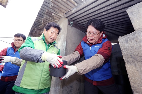 경남은행 손교덕 은행장(사진 오른쪽 두번째)이 안상수 창원시장(사진 오른쪽 첫번째)와 함께 ‘사랑의 연탄배달 행사’에 참가해 지원 대상 가구로 연탄을 옮기고 있다. 