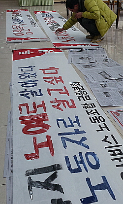 충북 음성군, 전국사무금융서비스노동조합 금왕농협분회 농성장에서 지난 26일 한 조합원이 자신들의 주장이 담긴 현수막을 만들고 있다.