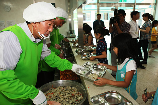 민병희 강원도교육감이 정선군의 한 초등학교에서 학생들에게 급식을 나눠주는 봉사를 하고 있다(2012년 7월).