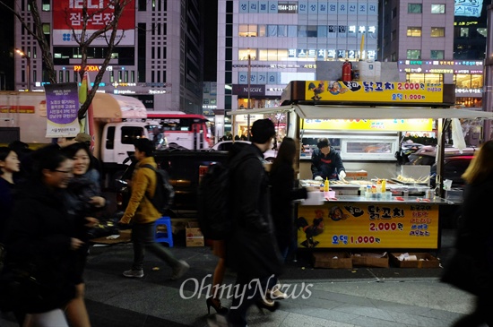  서울 지하철 2호선 강남역 인근에서 닭꼬치 노점상을 운영하는 박규석씨(가명, 33)가 닭꼬치를 굽고 있다. 박씨의 마차 위에 반쯤 찬 휘발유통과 소화기가 보인다.  