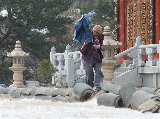  1일 함양 서암정사에서 한 신도가 눈바람에 날리는 우산을 힘겹게 부여잡고 걷고 있다.