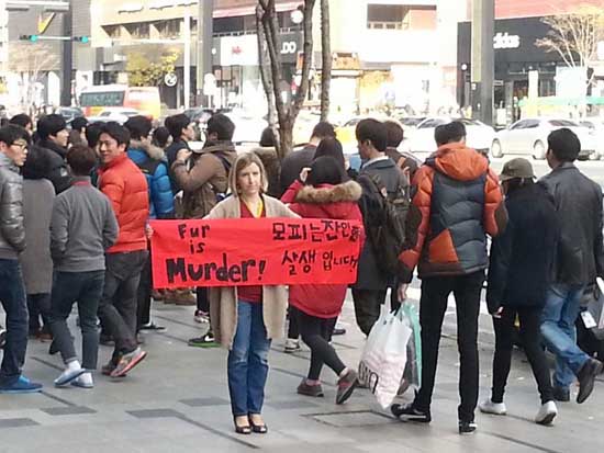 미국인 캐서린 버나드-김 씨가 강남 한복판에서 'Fur is Murder. 모피는 잔인한 살생입니다'라는 문구가 적힌 현수막을 들고 서 있다.