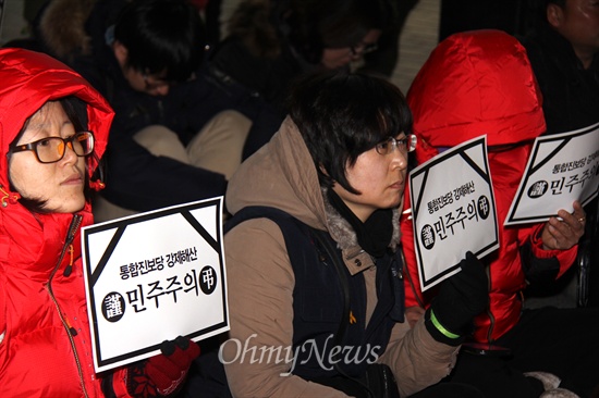  19일 저녁 창원 정우상가 앞에서 열린 "근조 민주주의, 민주수호 경남촛불문화제"에서 참가자들이 촛불과 피켓을 들고 앉아 있다.