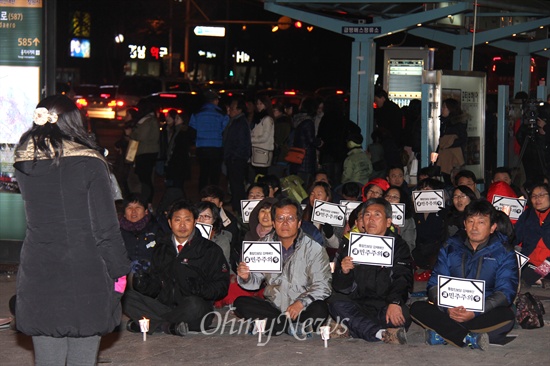  19일 저녁 창원 정우상가 앞에서 열린 "근조 민주주의, 민주수호 경남촛불문화제"에서 참가자들이 촛불과 피켓을 들고 노래 공연을 들으며 앉아 있다.