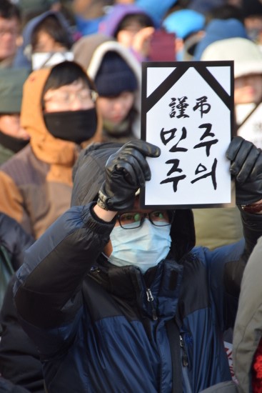 20일 오후 서울시 중구 청계광장에서 진행된 '민주주의 사형선고 박근혜독재 퇴진! 민주수호 국민대회'에서 한 한국진보연대 회원이 '謹弔 민주주의'라고 써진 피켓을 들고있다.