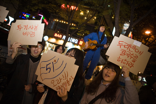 2010년 "두리반에 칼국수를 허하라"라는 피켓을 들고 51+ 공연을 홍보하고 있는 사람들의 모습