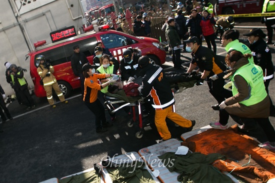 10일 오후 경기도 의정부 한 아파트 주차장에서 화재가 발생해 차량과 건물을 태운 상황에서 소방대원들이 사상자를 구조해 구급차로 옮기고 있다. 