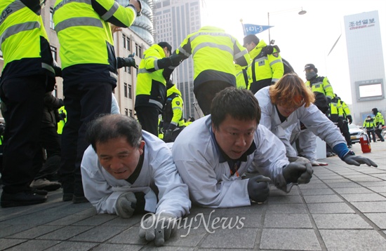 1월 11일, 비정규직 법·제도 철폐를 위해 오체투지 행진을 이어가고 있는 금속노조 쌍용자동차 해고노동자와 연대단체 참가자들이 서울 종로구 세종로사거리 앞에서 경찰들의 저지로 행진이 막히자, 경찰들 사이로 땅을 기어가고 있다.