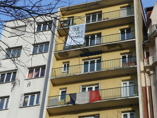 한 건물에 내걸린 피켓('샤를리가 살아남길 바란다'라는 뜻)과 아래 층에 걸린 프랑스 국기. 