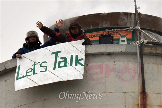 지난 1월 14일 쌍용자동차 해고노동자인 금속노조 쌍용차지부 김정욱 사무국장과 이창근 정책기획실장이 깔개 위에 청테이프로 'Let's Talk'이라는 글자를 만들어 들어보이고 있다.