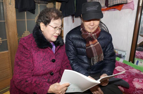 박정열 할머니가 배우자인 노유근 할아버지와 함께 자신이 쓴 글을 읽고 있다.