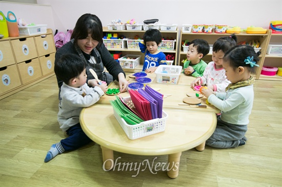 푸른숲 어린이집 교사가 어린이들과 함께 밀가루 반죽으로 만든 점토 놀이를 하고 있다.