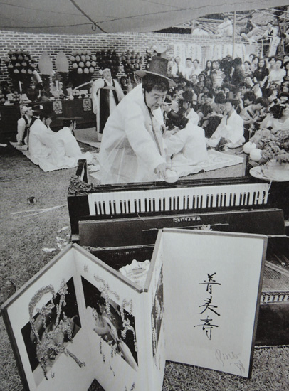 1990년 백남준 요셉 보이스 추모 굿 장면. 보이스가 백남준 첫 전시에서 박살을 낸 피아노가 보이고 백남준이 그에게 지어준 한국 이름 '보이수(普夷壽)'가 적힌 병풍
