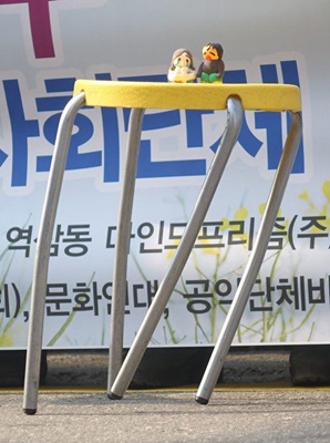 보건의료노조 마인드프리즘지부와 시민단체가 주최한 기자회견에서 사용된 소품으로, 해고자 김미성씨와 딸이 만든 찰흙 인형이 다리가 비틀어진 의자 위에 위태롭게 놓여 있다.