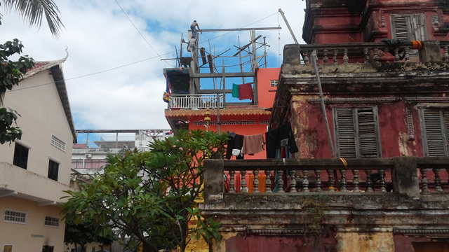 저 위에 사람이 있다. 집을 짓고 있다. 위태위태하다. 앞쪽의 불교사원엔 빨래가 당연하게 걸려있다. 프놈펜 시내 곳곳엔 많은 불교사원이 있다. 