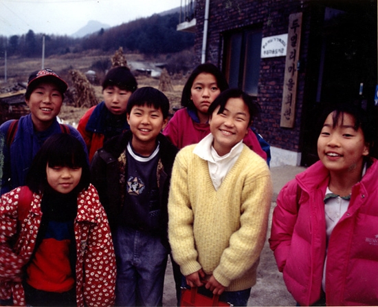 1994년 두밀분교 학생들이 마을회관 앞에서 환하게 웃고 있다. 당시 두밀분교 폐교 반대 운동을 담은 홍형숙 감독의 다큐멘터리 영화 <두밀리 - 새로운 학교가 열린다>(1995)의 한 장면이다.