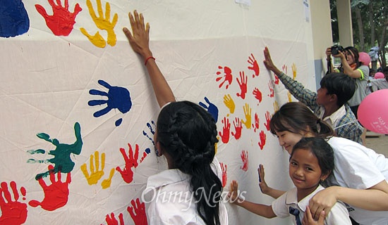 해피무브 봉사활동 학생들과 프라삿쿨 학생들이 서로 학교 벽면에 손도장을 찍으며 서로에게 감사의 인사를 전하고 있다.