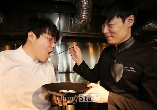  올리브쇼의 최현석 셰프(오른쪽)가 10일 오후 서울 신사동 엘본더테이블 신사점에서 오세득 셰프에게 요리한 음식을 먹여주고 있다. 