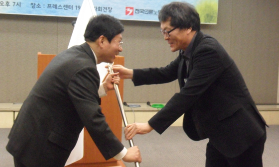 강성남 전언론노조위원장이 전국언론노조 깃발을 김환균 언론노조위원장에게 전달하고 있다.