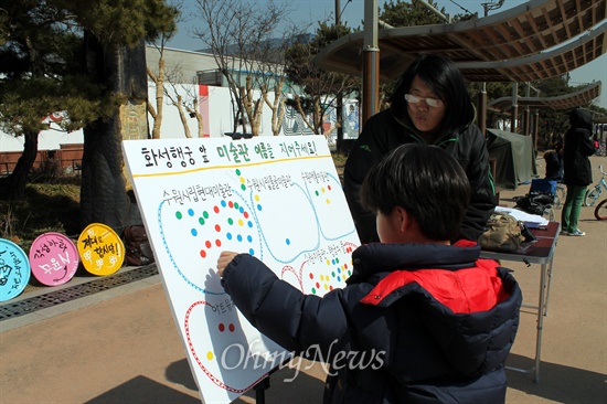 수원 시립미술관 공사현장 앞에서 한 어린이가 마음에 드는 미술관 이름에 스티커를 붙이고 있다. 