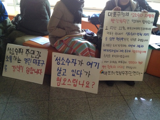 마레연 회원들이 마포구청의 성소수자 인권지지 현수막 게시 거부에 항의하는 피켓을 들고 있다.