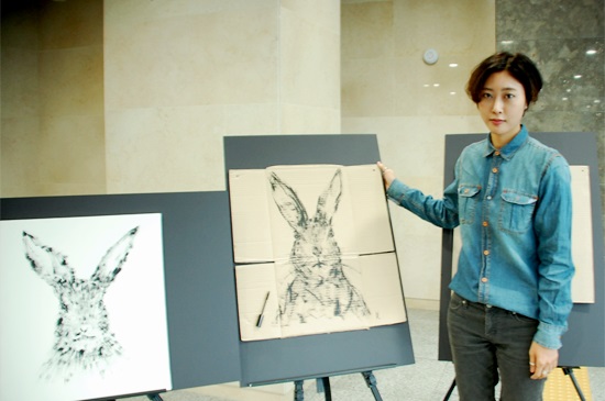 강보라(27·국민대 그린디자인 소속) 작가가 폐마스카라로 그린 토끼 형상 작품 앞에서 포즈를 취하고 있다. 