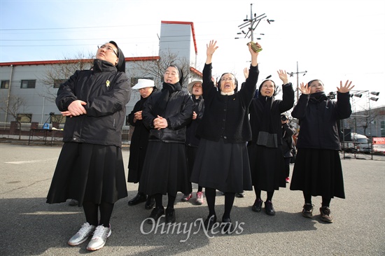 희망행동에 참여한 수녀들이 굴뚝농성중인 이창근씨를 향해 기도를 한 뒤 손을 흔들고 있다.
