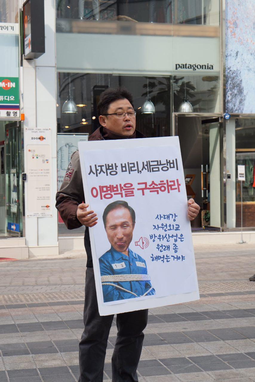 한 회원이 광복로에서 피켓을 들고 이명박 고발운동을 홍보하고 있다.
