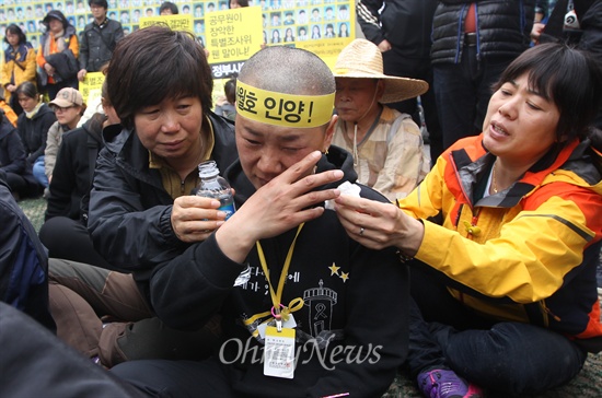 세월호 참사 희생자 오영석 학생의 어머니 권미화 씨가 오후 서울 종로구 광화문 세월호 농성장에서 정부가 발표한 배상·보상안에 반대하며 유가족과 함께 삭발하자, 이를 지켜보고 있던 시민들이 눈물을 닦아주며 위로하고 있다.