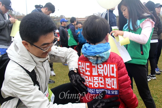  5일 합천공설운동장에서 열린 제14회 합천벚꽃마라톤대회에서 한 학부모가 아이 등에 '급식도 교육이다'는 내용의 몸벽보를 붙여주고 있다.