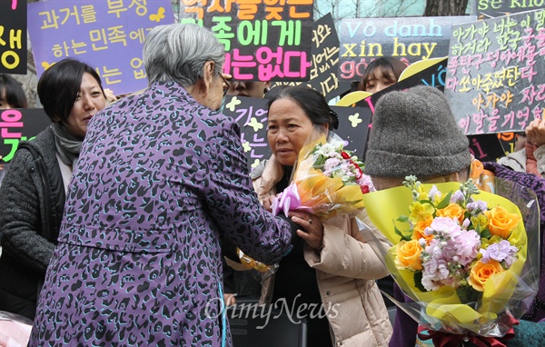 일본군 위안부 피해자 김복동 할머니가 8일 오후 서울 종로구 일본대사관 앞에서 열린 '일본 위안부 문제 해결을 위한 1173차 수요집회'에서 베트남전 한국군 민간인학살 피해자 응우옌 티 탄(NGUYEN THI THANH) 씨에게 꽃다발을 건네주고 있다.