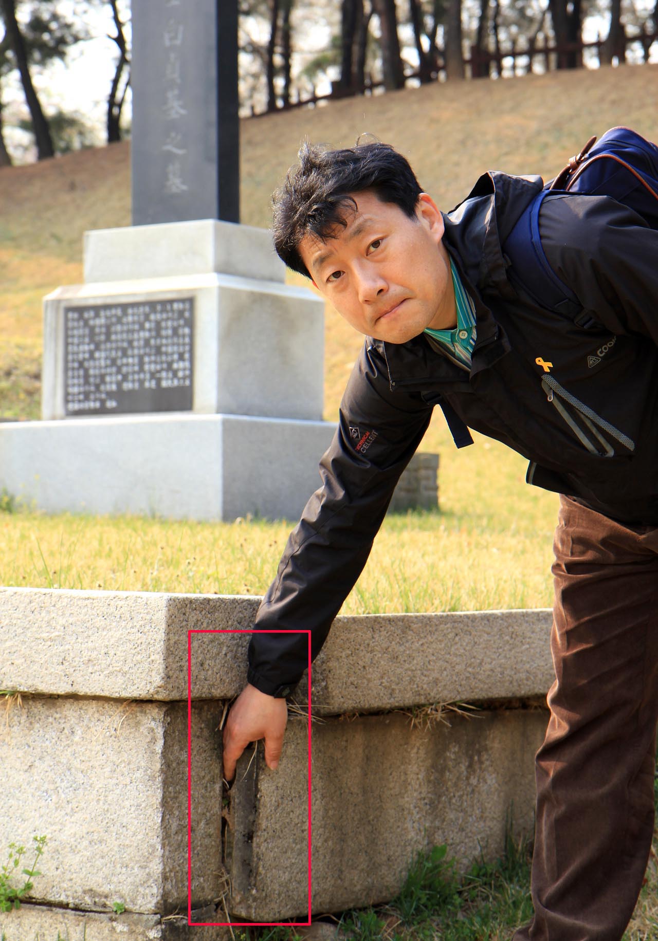 방학진 민족문제연구소 사무국장이 삼의사 묘역의 벌어진 축대에 손을 넣어 보이고 있다.
