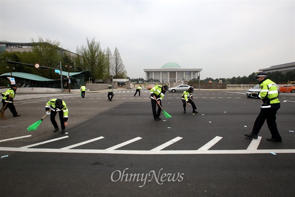 빗자루를 든 경찰들이 동원되어 국회 주위에 뿌려진 전단을 수거하고 있다.