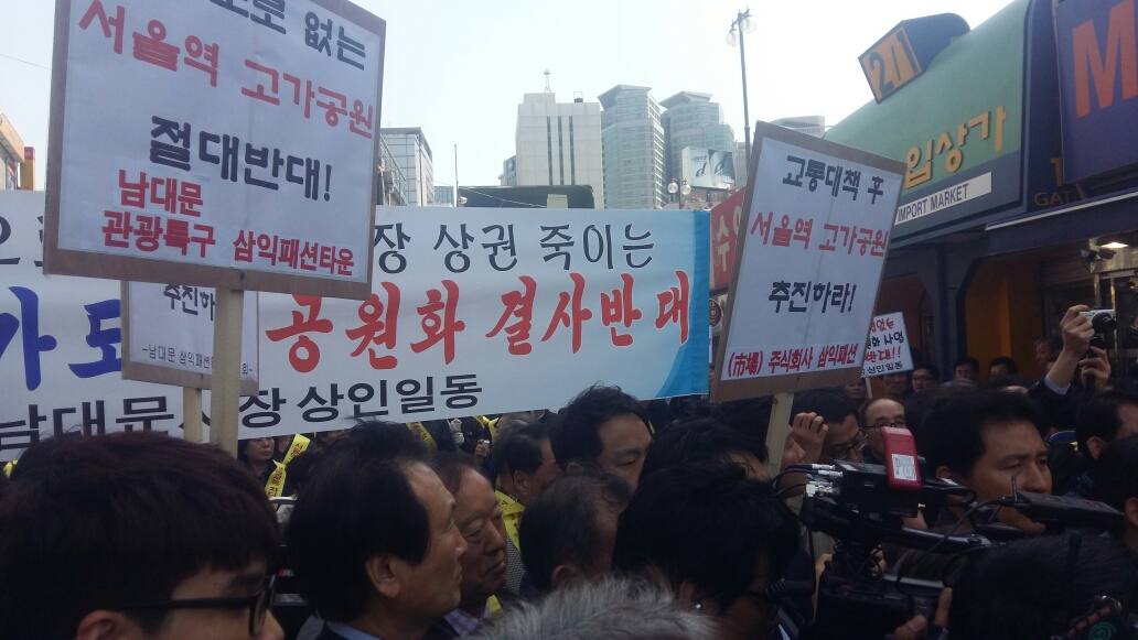 박원순 서울시장이 17일 오전 남대문시장을 방문하자 시장 상인들이 서울역고가 공원화 사업 반대 손팻말을 들고 항의하고 있다.