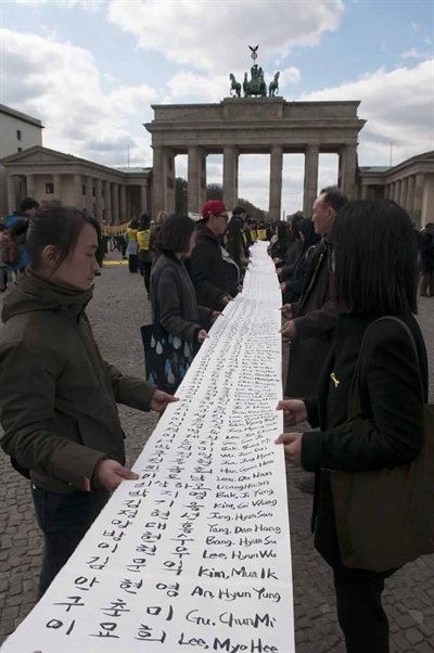 세월호 희생자 304명의 이름이 빼곡하게 적혀있는 종이를 베를린 추모집회 참가자들이 들고 있다.
