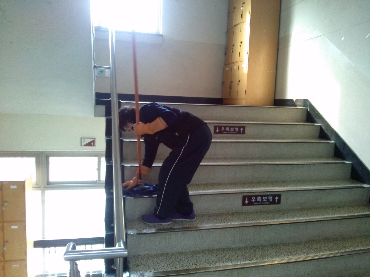 사수가 자신의 청소구역 중 하나인 2층 계단을 대걸레로 닦고 있다.