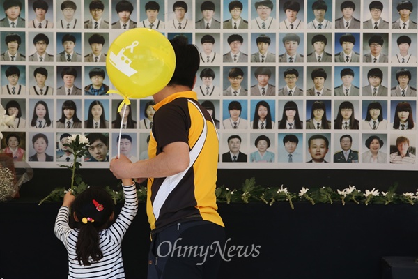 25일 오후 서울 광화문광장에 마련된 세월호참사 합동분향소에 아빠와 함께 온 어린이가 헌화하고 있다.