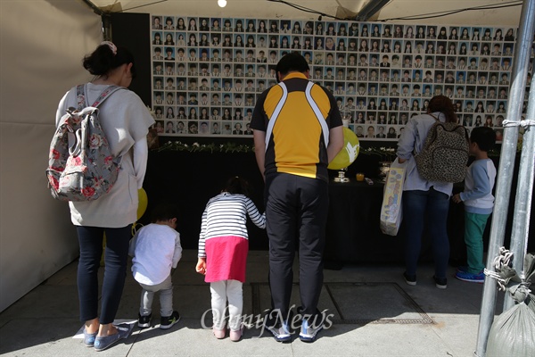 25일 오후 서울 광화문광장에 마련된 세월호참사 합동분향소에 부모와 아이들이 헌화한 뒤 고개숙여 묵념하고 있다.