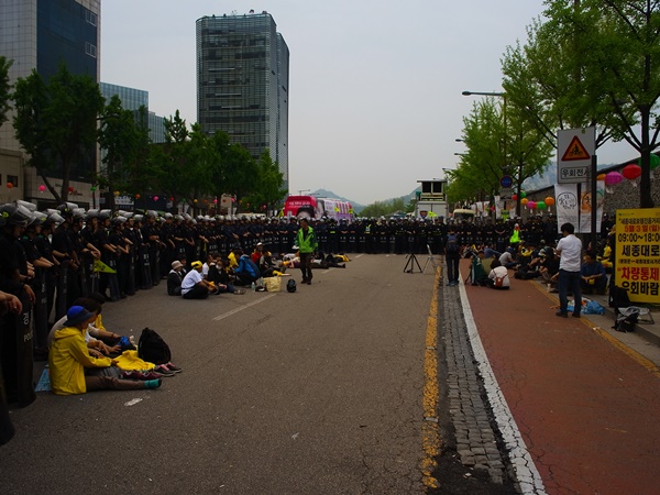 이 길을 지나가려는 사람들은 인도 전부와 차도 일부를 막아 버린 경찰 때문에 차도 바깥으로 다녀야 했다.