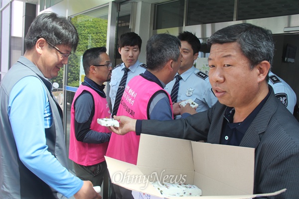  홍준표 경남지사가 8일 오전 성완종 리스트와 관련해 검찰에 출석한 가운데, '경남도청과 공공기관 이전반대 창원시민대책위' 변상기 공동집행위원장이 경남도청 문 앞에서 '준표표 무상콩떡'이라 적힌 떡을 나눠주고 있다.