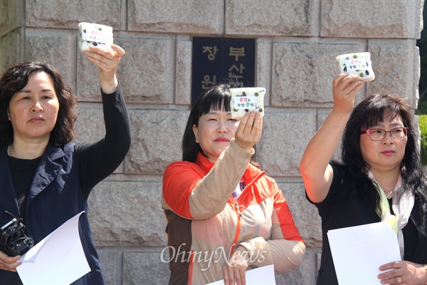  홍준표 경남지사가 8일 오전 성완종 리스트와 관련해 검찰에 출석한 가운데, '경남도청과 공공기관 이전반대 창원시민대책위' 변상기 공동집행위원장이 '준표표 무상콩떡'이라 적힌 떡을 만들어 와 창원지방검찰청 앞에서 나눠주었고 학부모들이 들어 보이고 있다.