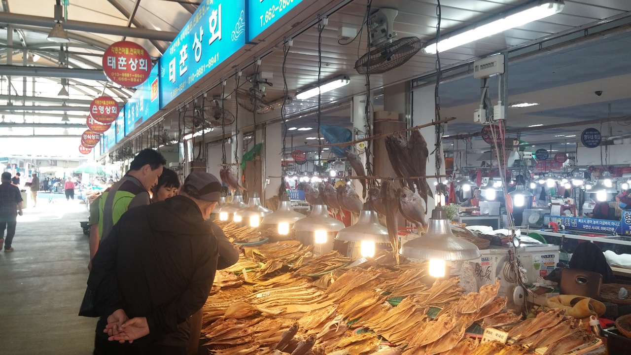  새로운 먹거리로 떠오른 여수수산물시장 풍물거리에서 관광객 일행이 마른 생선을 사고 있다.